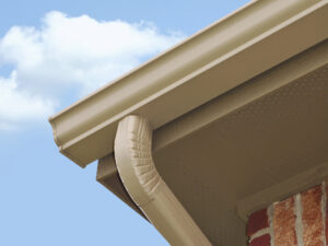 A close-up of a beige gutter system and a downspout. 