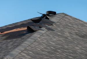 A weather-damaged residential roof with curling shingles.