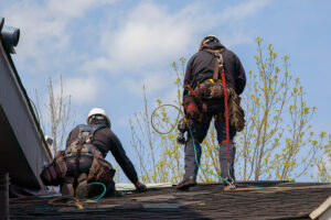 Two professional roofers working on a residential roof.
