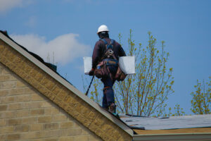 A professional roofer, carrying roofying materials on a residential roof.